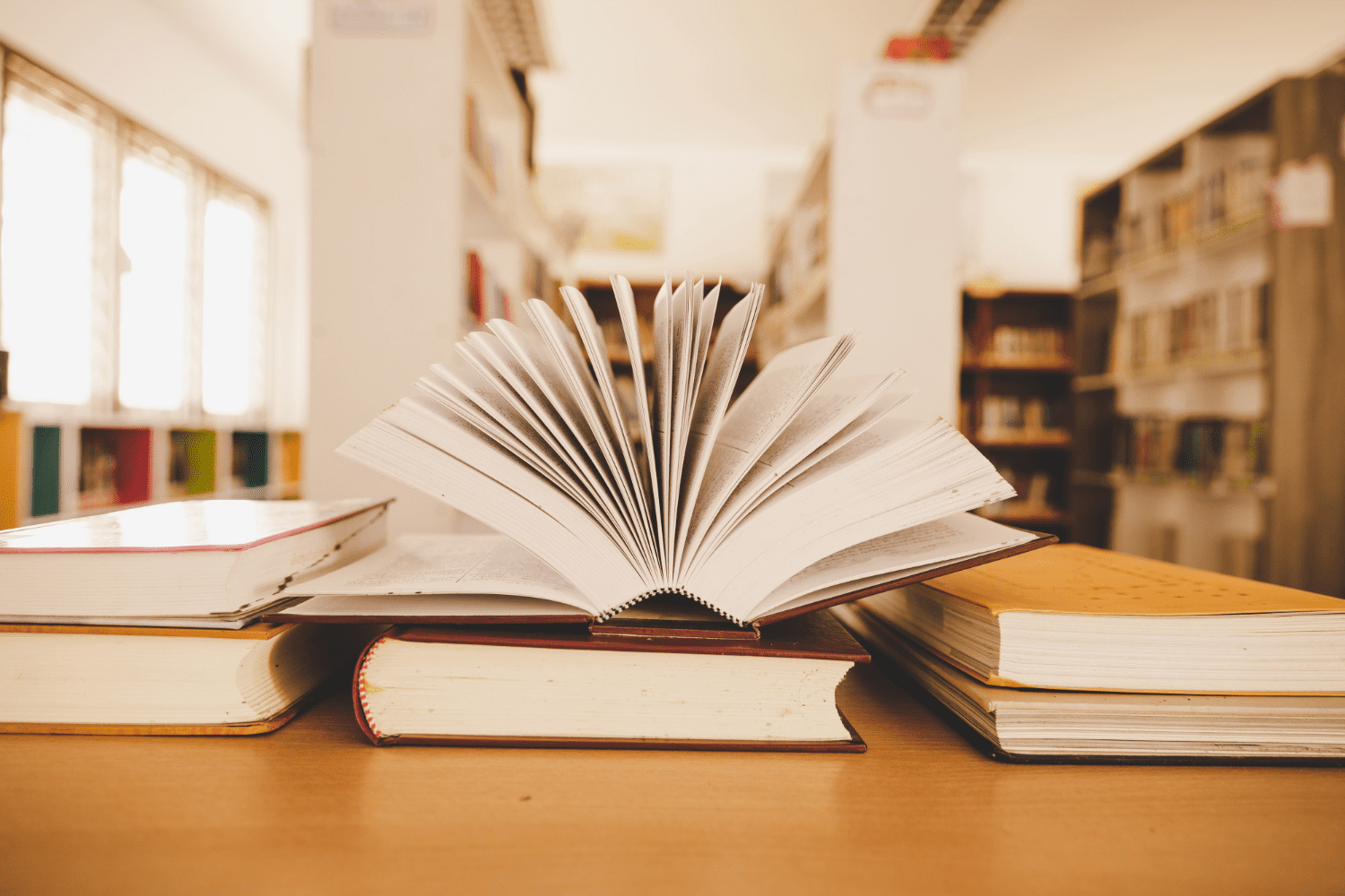 Book in library with old open textbook, stack piles of literature text archive on reading desk<br />
